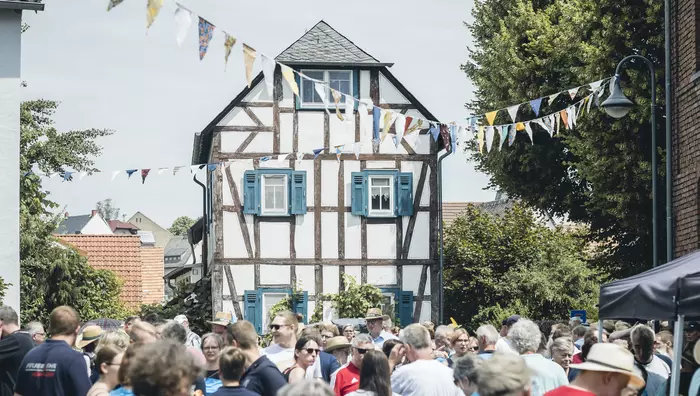 Menschen im Dorf Mensfelden 2023 mit Fachwerkhaus