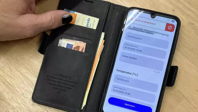 Ein angeschaltetes Handy liegt auf einem Tisch und zeigt die Nutzungsoberflächer der Herz-App.