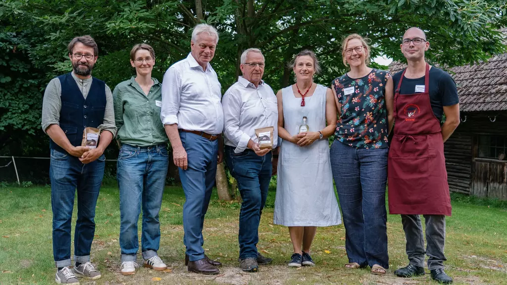 3 Frauen und 4 Herren stehen nebeneinander auf einer Wiese.