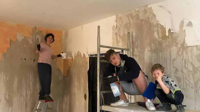 Jugendliche renovieren die Wände des Pfarrhauses.