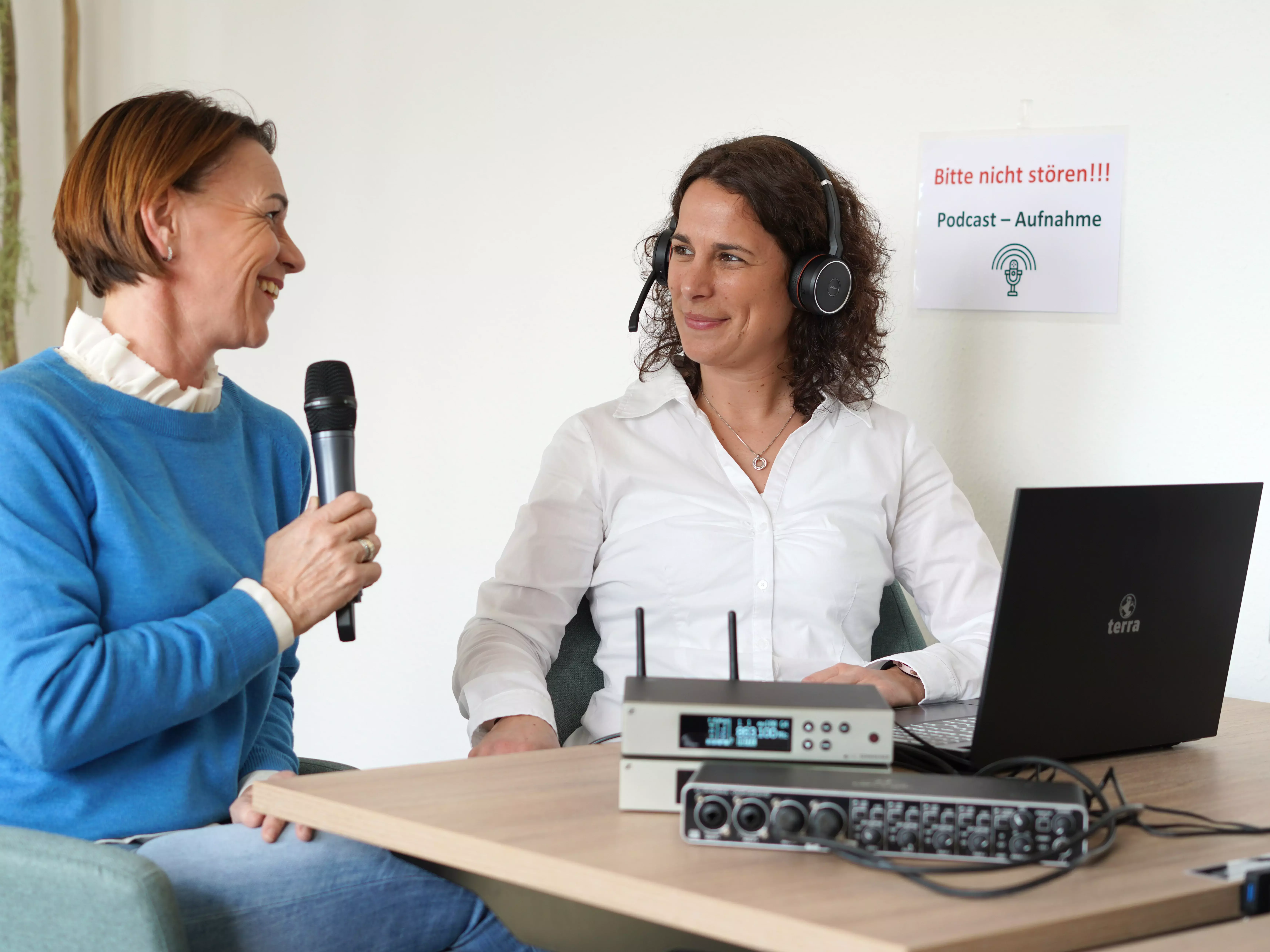 Zwei Frauen bei der Aufnahme eines Podcasts vor einem Laptop und Tontechnik