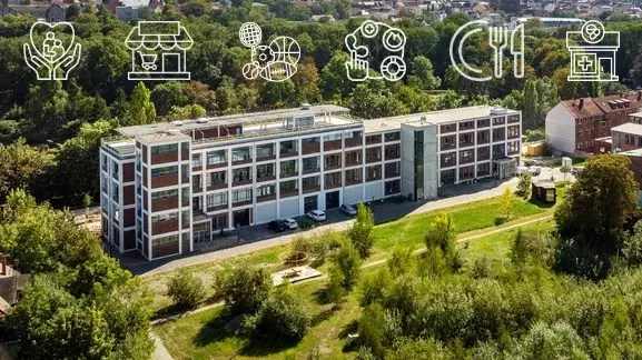 Ein mehrstöckiges Gebäude umgeben von grüner Wiese und einem kleinen Walld