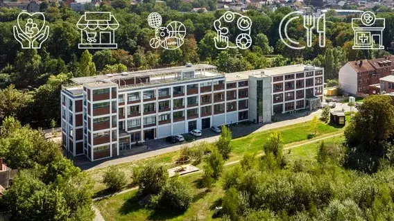 Ein mehrstöckiges Gebäude umgeben von grüner Wiese und einem kleinen Walld