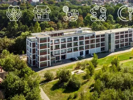 Ein mehrstöckiges Gebäude umgeben von grüner Wiese und einem kleinen Walld