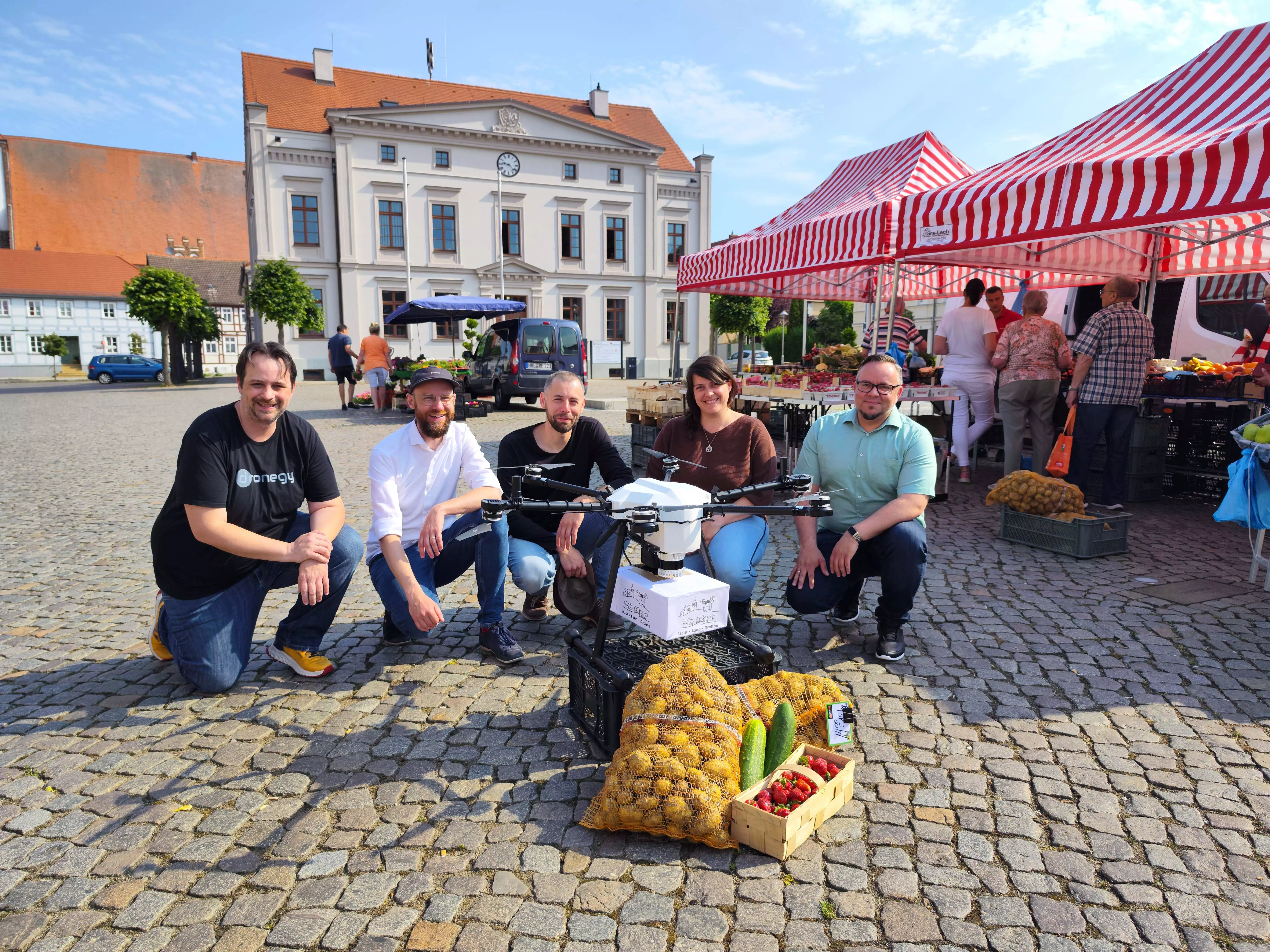 5 Mitarbeitende des Projekts knien vor einer Lieferdrohne