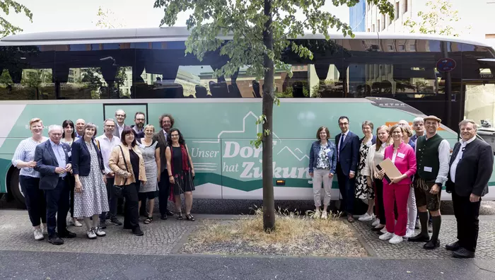 Die Jurymitglieder stehen mit Bundesminister Cem Özdemir vor dem "Unser Dorf hat Zukunft"-Bus