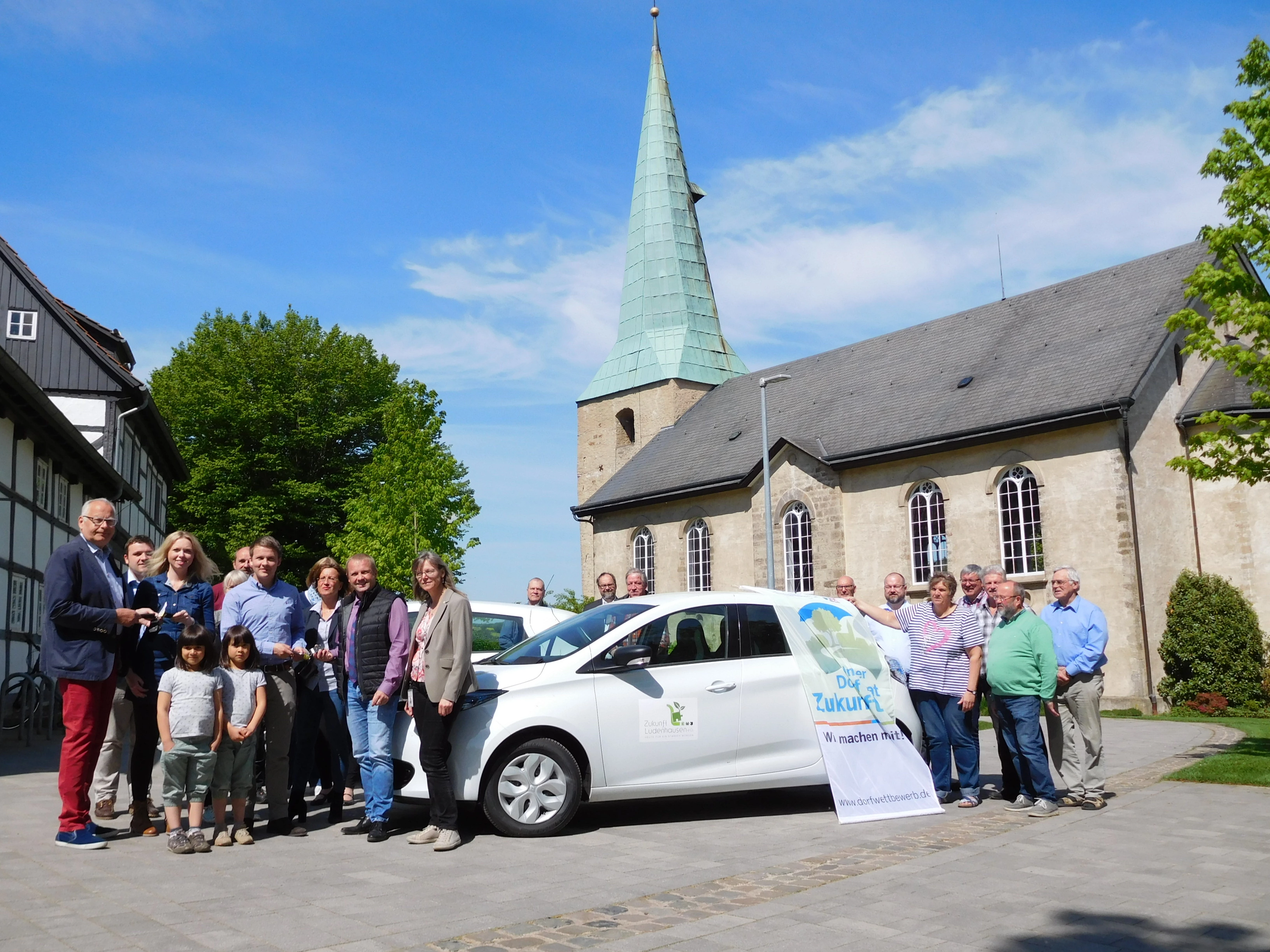 Bewohnerinnen und Bewohner von Lüdenhausen vor einem Elektroauto