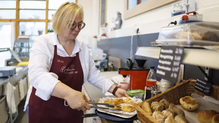 Frau holt Brötchen aus dem Ofen