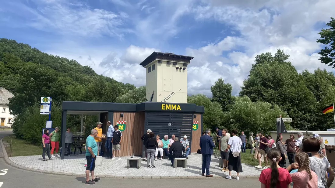 Frauen, Männer und Kinder stehen auf dem Platz vor der eröffneten EMMA in der Sonne.