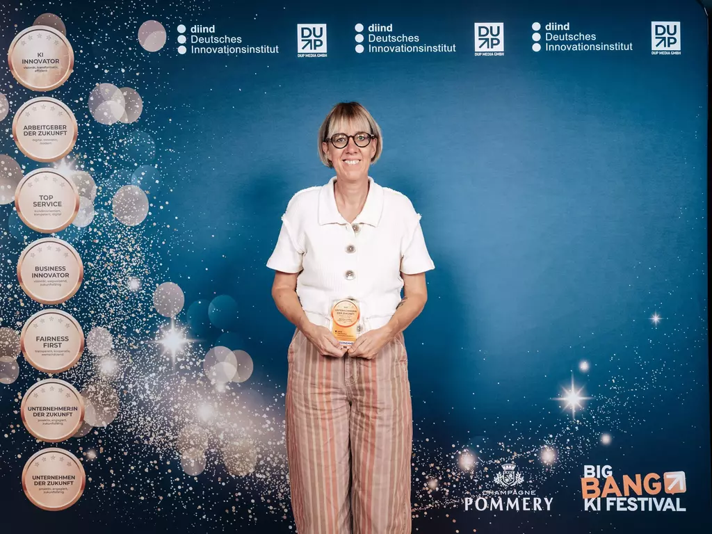 Die Preisträgerin steht auf der Bühne mit ihrer Auszeichnung in der Hand.