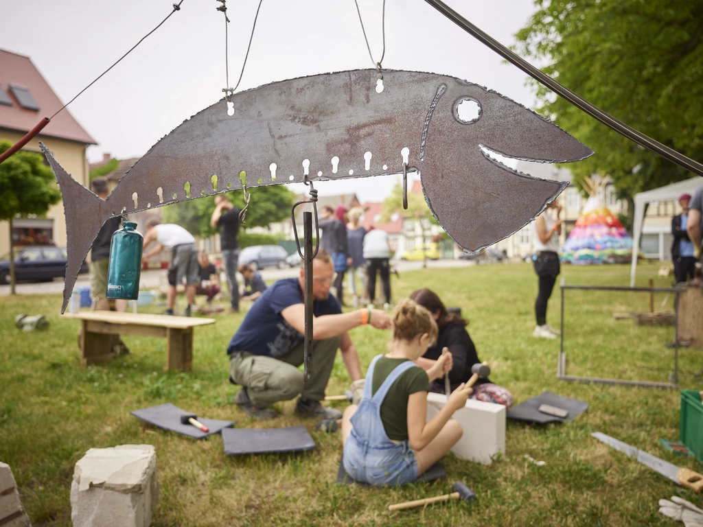 Menschen bei künstlerischen Handwerksarbeiten auf einer Sommerwiese