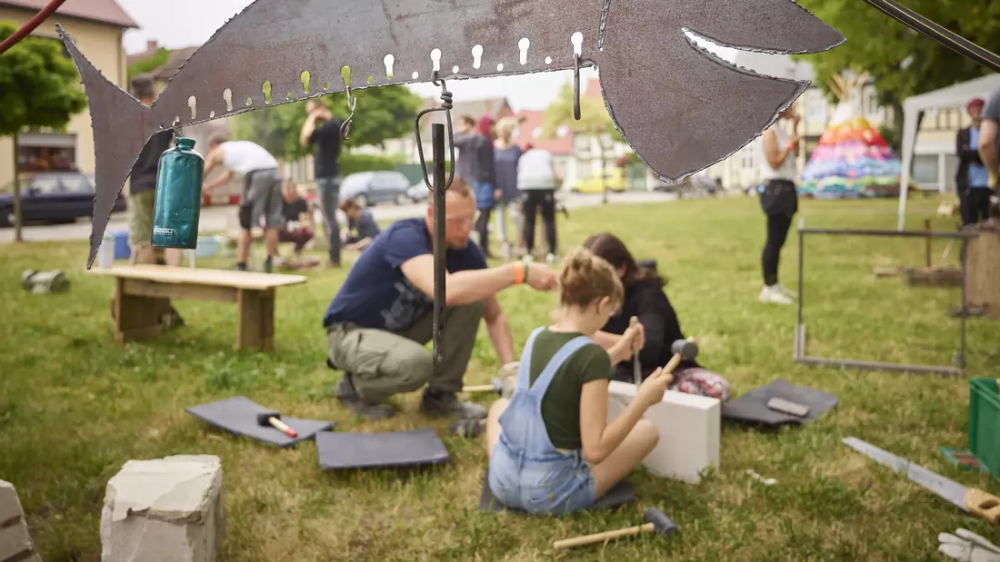 Menschen bei künstlerischen Handwerksarbeiten auf einer Sommerwiese