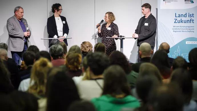 Teilnehmende diskutieren auf der Bühne