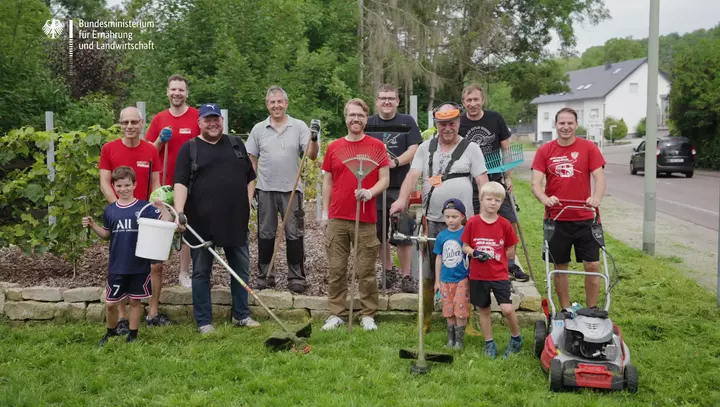 Bewohner des Dorfes Bliesmengen-Bolchen stehen mit Gartengeräten auf einer Wiese