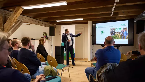Ein Mann präsentiert eine Präsentation auf einem Bildschirm vor Publikum