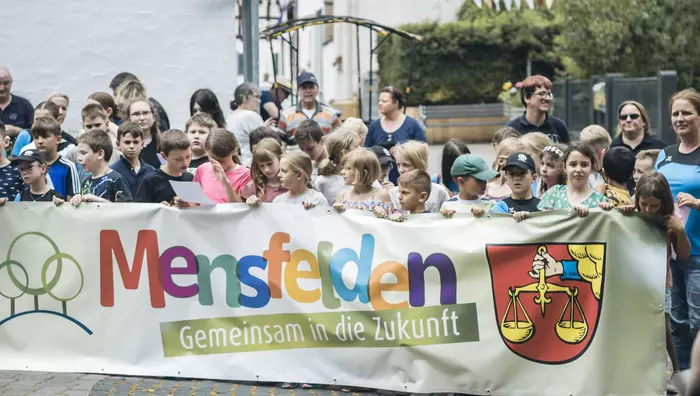 Bewohner des Dorfes Mensfeln halten einen Banner mit der Aufschrift "Mensfelden - Gemeinsam in die Zukunft" hoch