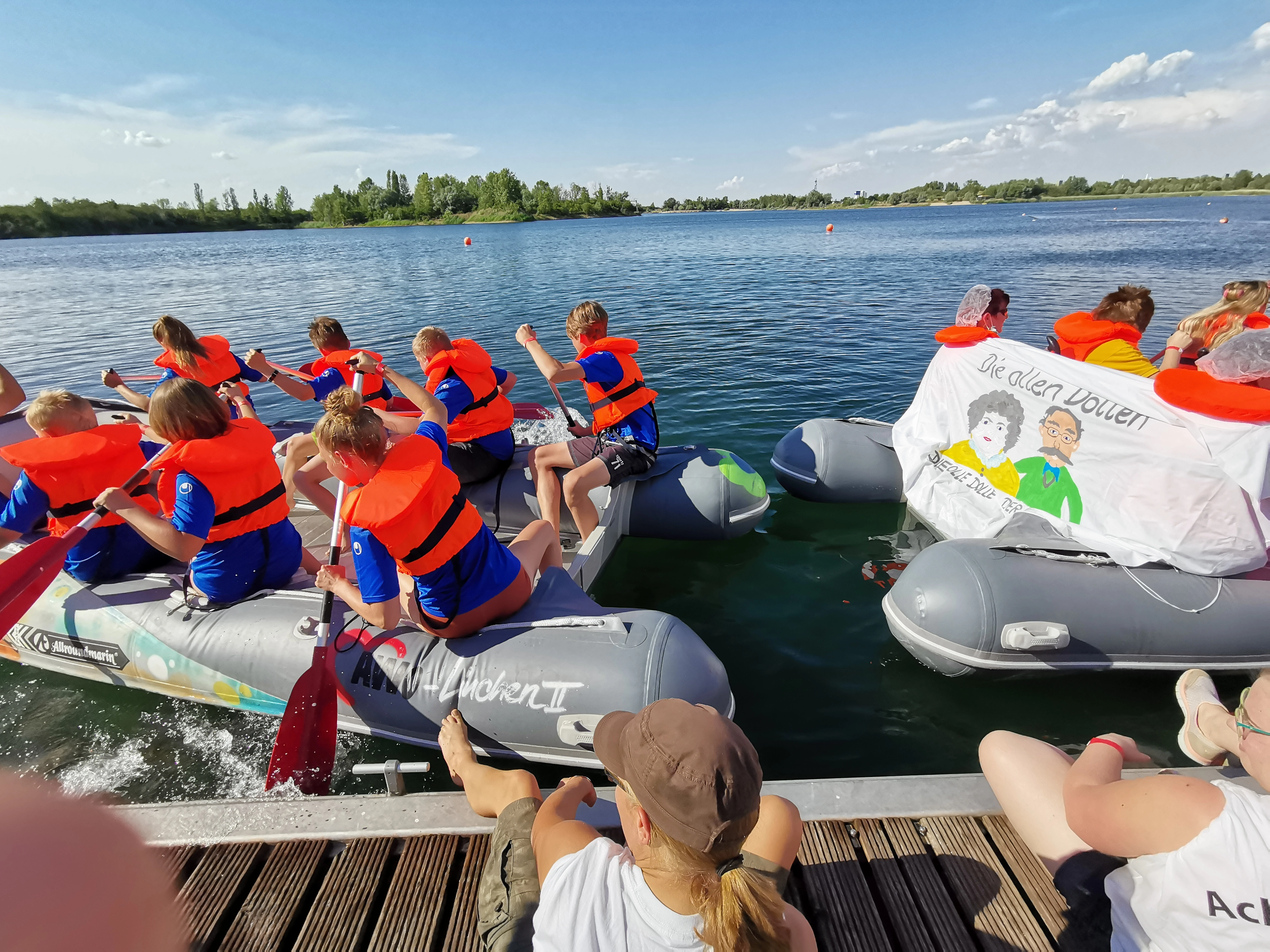 Kinder mit Rettungswesten bei einer Bootsrallye auf einem See