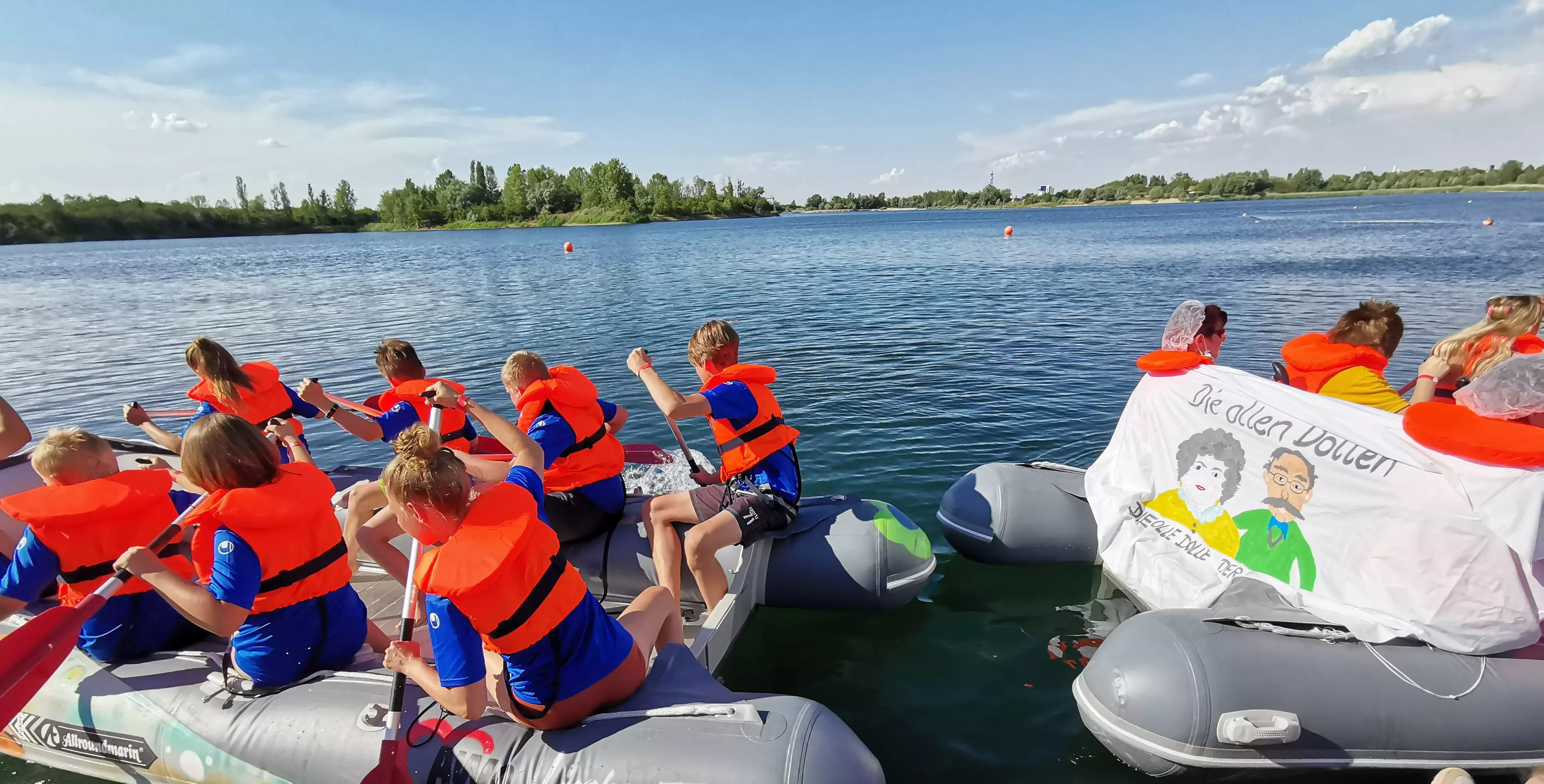 Kinder mit Rettungswesten bei einer Bootsrallye auf einem See