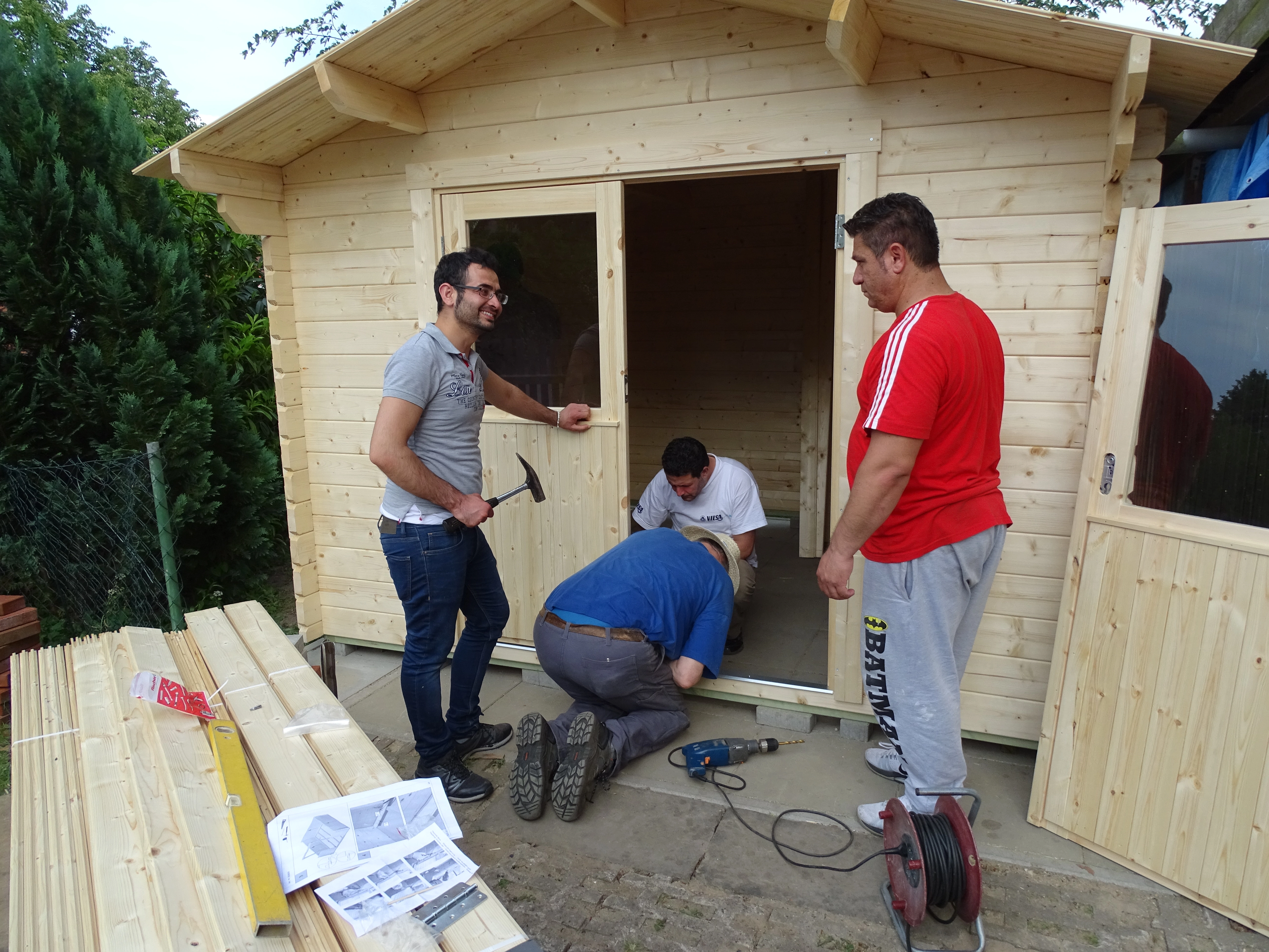 4 Männer beim Aufbau einer Holzhütte