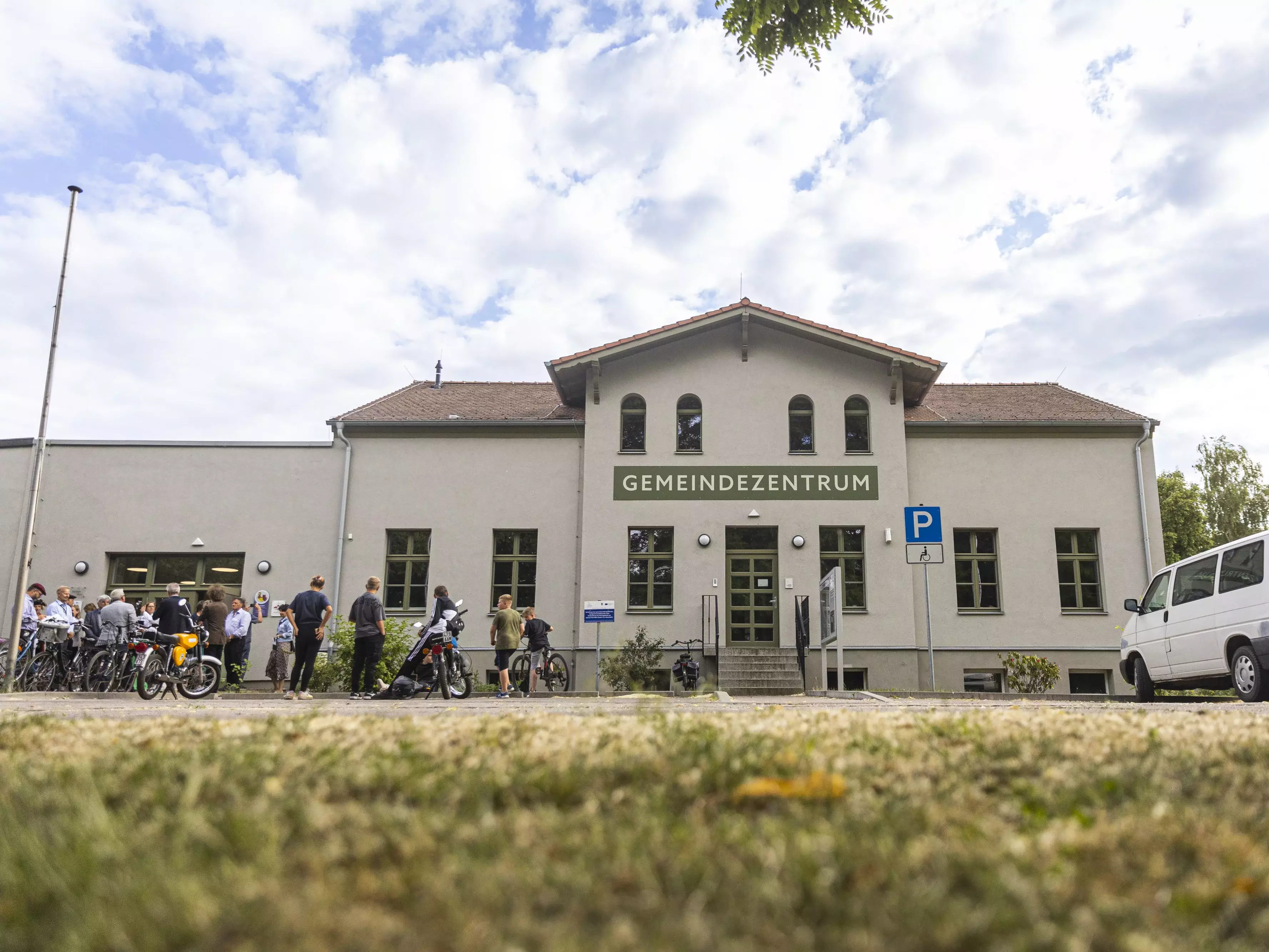 Menschen mit Fahrrädern stehen vor dem Gemeindezentrum.