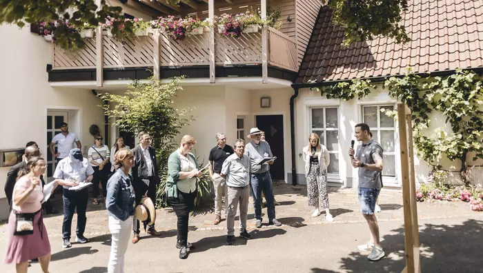 Ein Mann mit Mikrofon steht vor einer Gruppe Menschen.