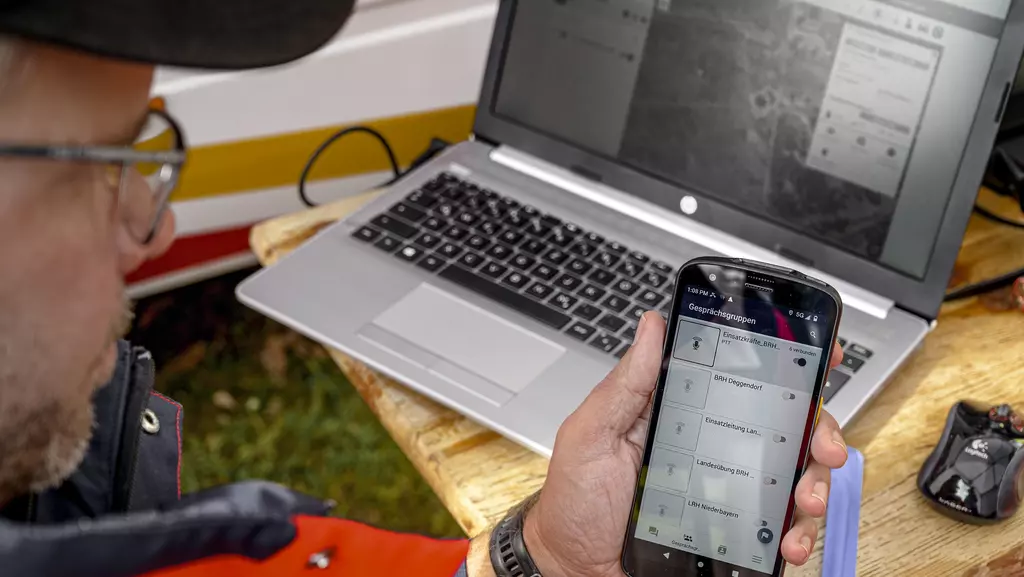 Mitarbeiter der Rettungsstaffel hält Handy in der Hand.