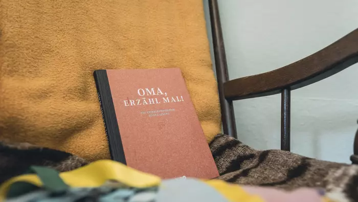 Auf einem Stuhl liegt ein Buch mit dem Titel "Oma, erzähl mal"