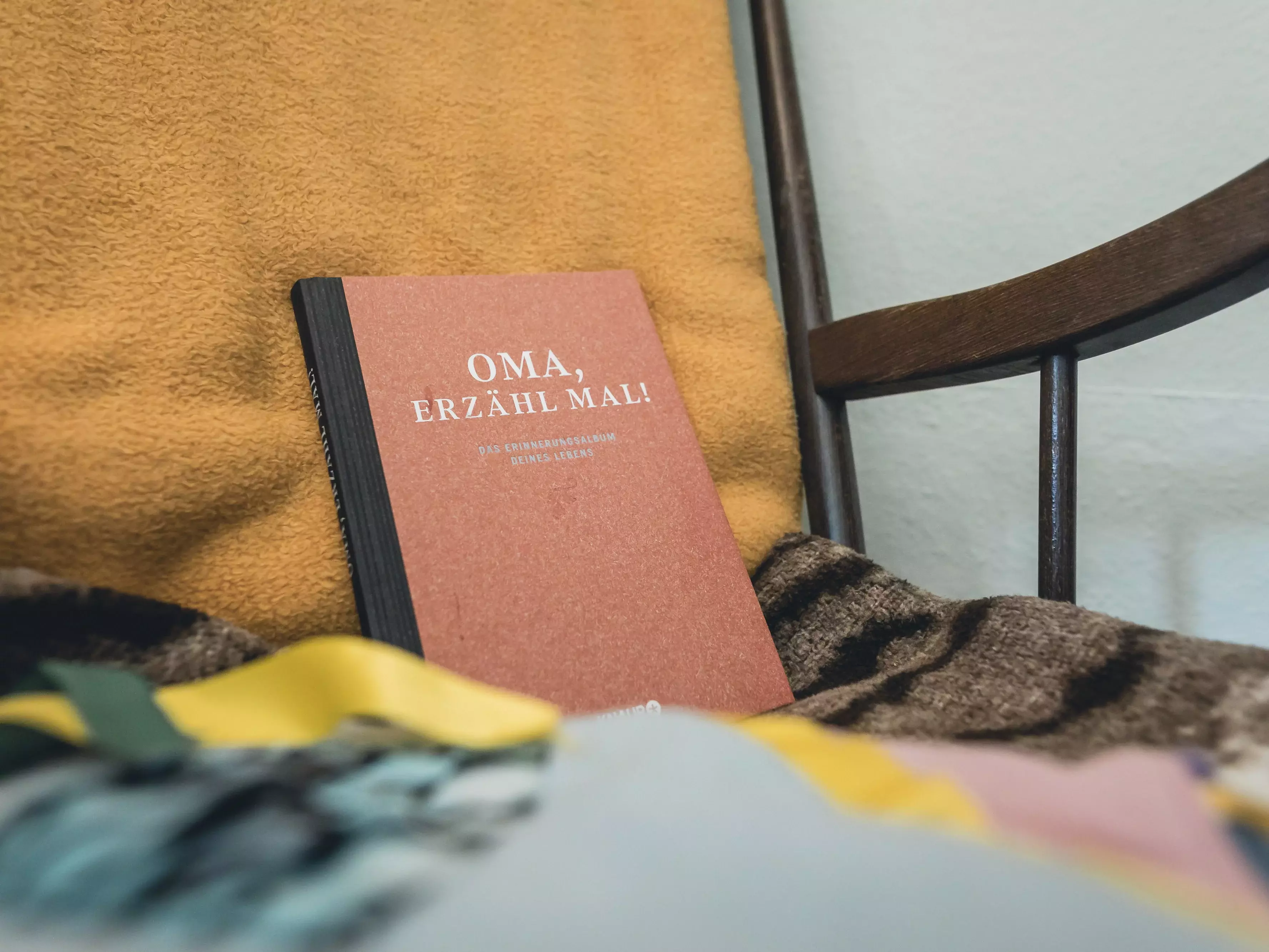 Auf einem Stuhl liegt ein Buch mit dem Titel "Oma, erzähl mal"