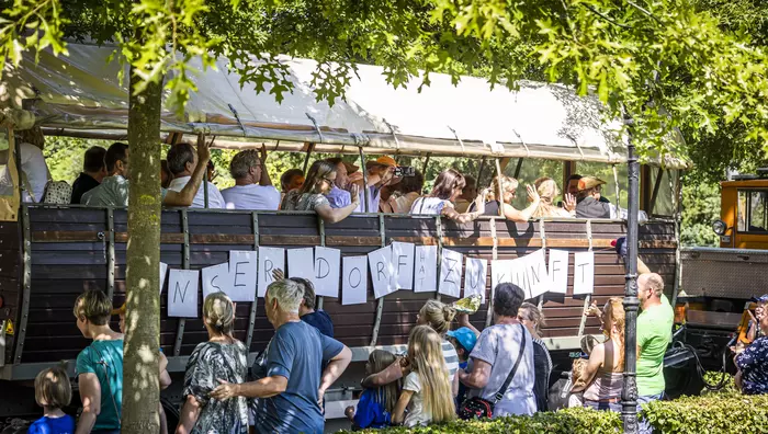 Menschen fahren in einem Planwagen mit der Aufschrift "Unser Dorf hat Zukunft"