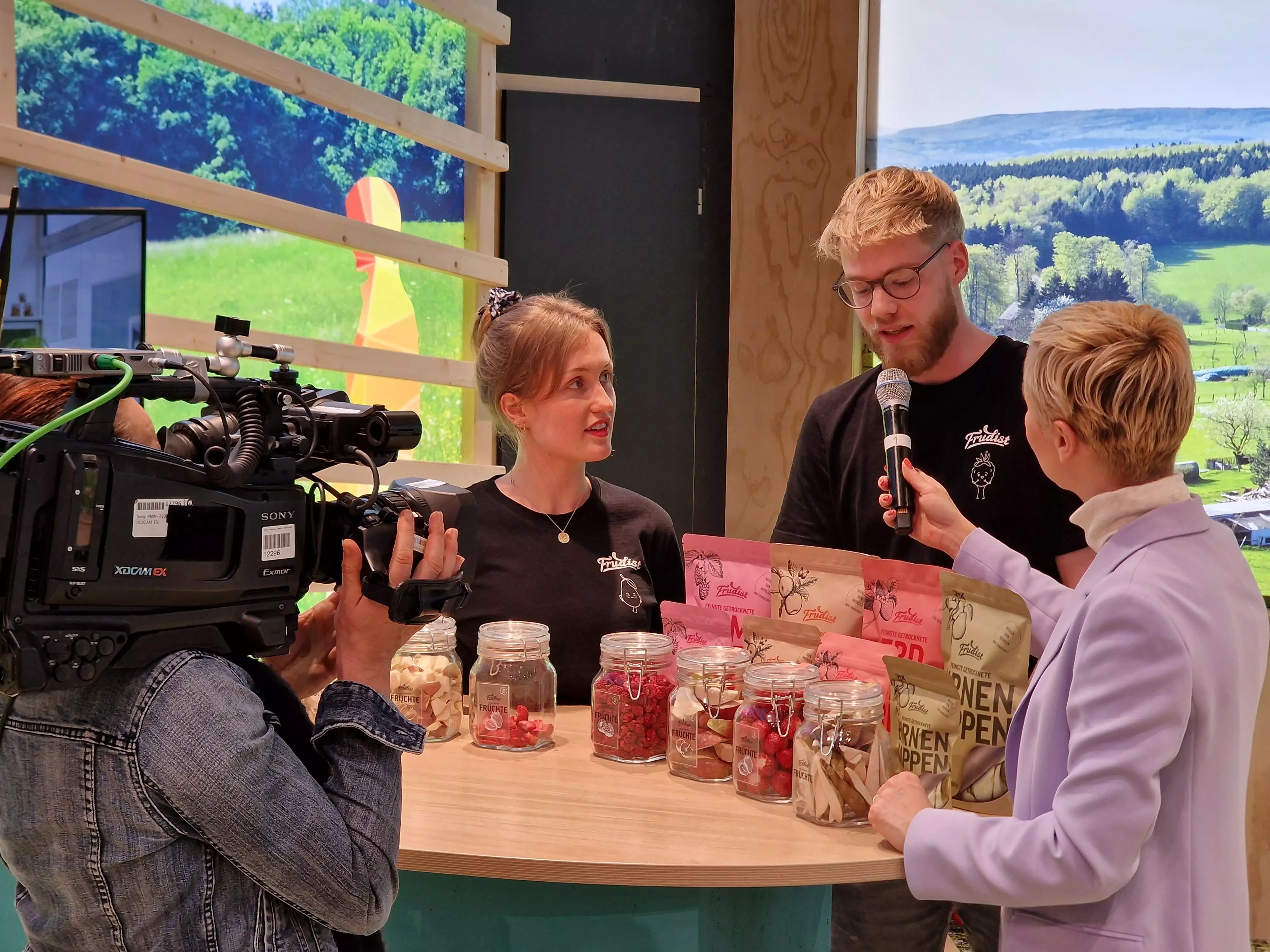Zwei Mitarbeitende des Projekts "Frudist" mit Moderatorin am Messestand