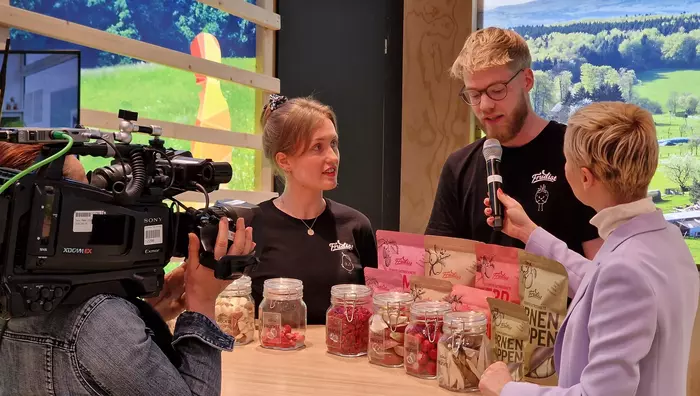 Zwei Mitarbeitende des Projekts "Frudist" mit Moderatorin am Messestand
