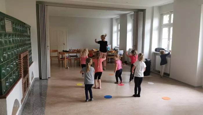 Eine Gruppe von Kindern turnt mit einer Trainerin.