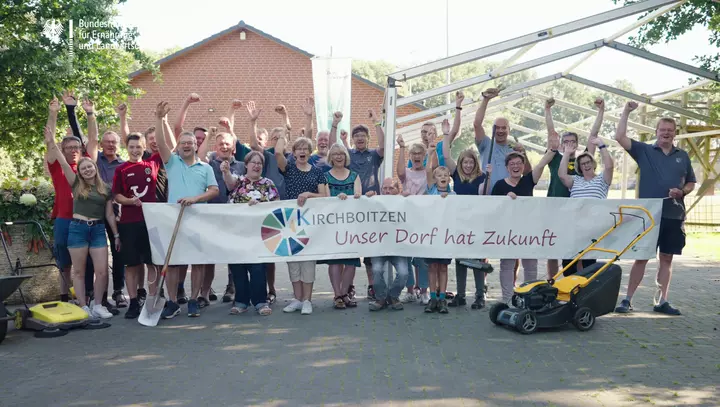 Bewohnerinnen und Bewohner von Kirchboitzen halten gemeinsam ein Banner mit "Unser Dorf hat Zukunft" in den Händen
