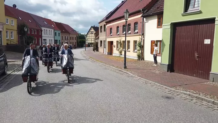 Bundesminister Alois Rainer, Bürgermeister Matthias Radtke und weitere Teilnehmende fahren mit Lastenrändern durch Röbel/Müritz