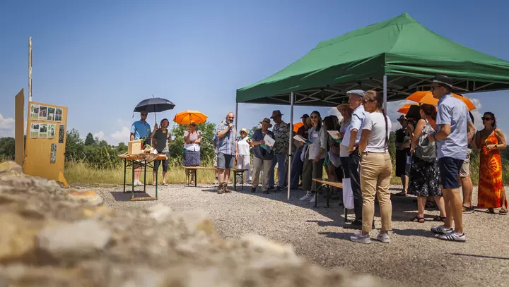 Menschen stehen in der Sonne und schauen sich Pläne an