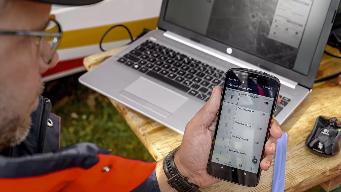 Mann der Rettungsstaffel hält Handy in der Hand