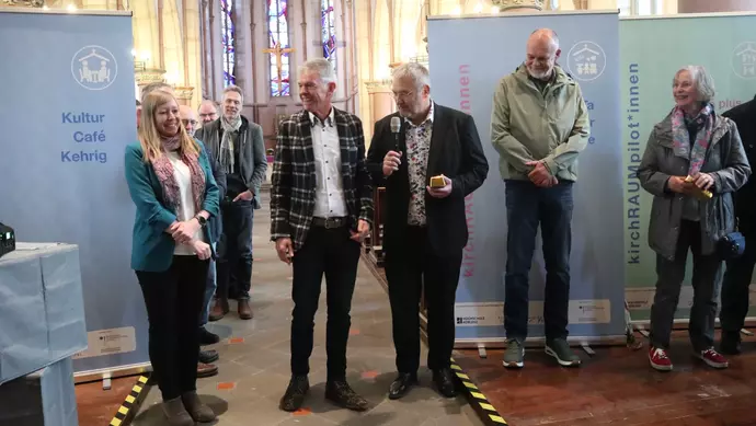 Mehrere Personen stehen in einer Kirche.