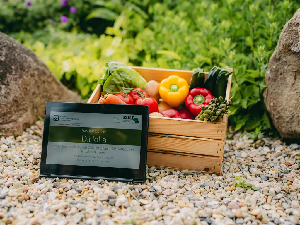 Ein Tablet lehnt an einer Holzkiste voller Gemüse.