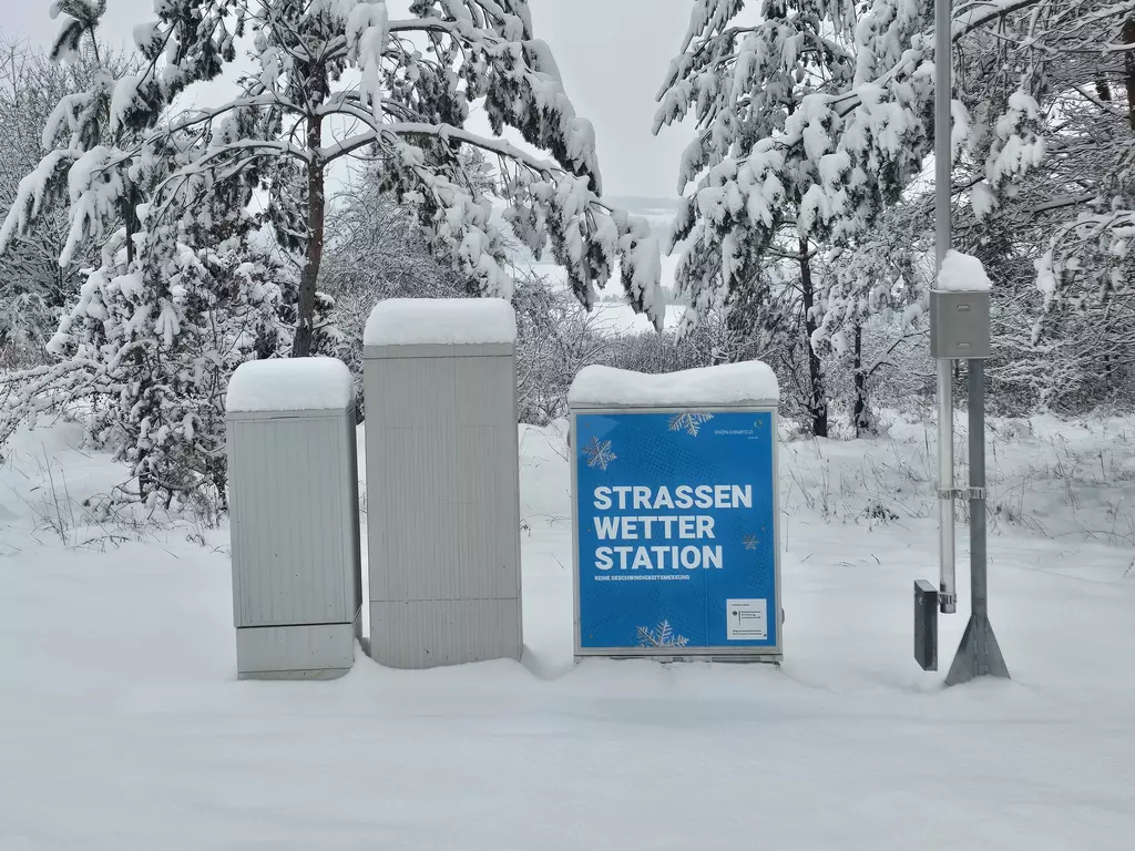 Mehrere Messstationen stehen vor verschneiten Bäumen.