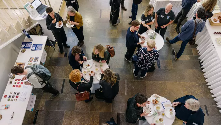 Teilnehmede der Faktor K Konferenz während der Mittagspause an Stehtischen im Gespräch