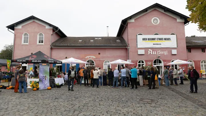 Ansicht des Bahnhofs von außen mit Leuten