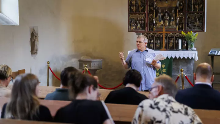 Mann redet vor Menschen in einer Kirche in Westdorf